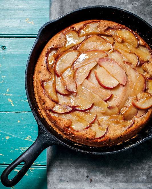 Apple cake in a cast iron skillet on a rustic wooden surface